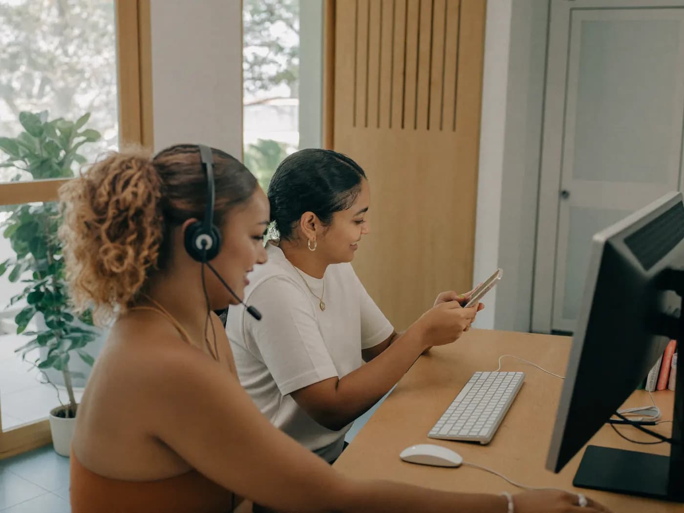 Recepcionistas de uma clínica atendendo pacientes pelo celular e pelo computador