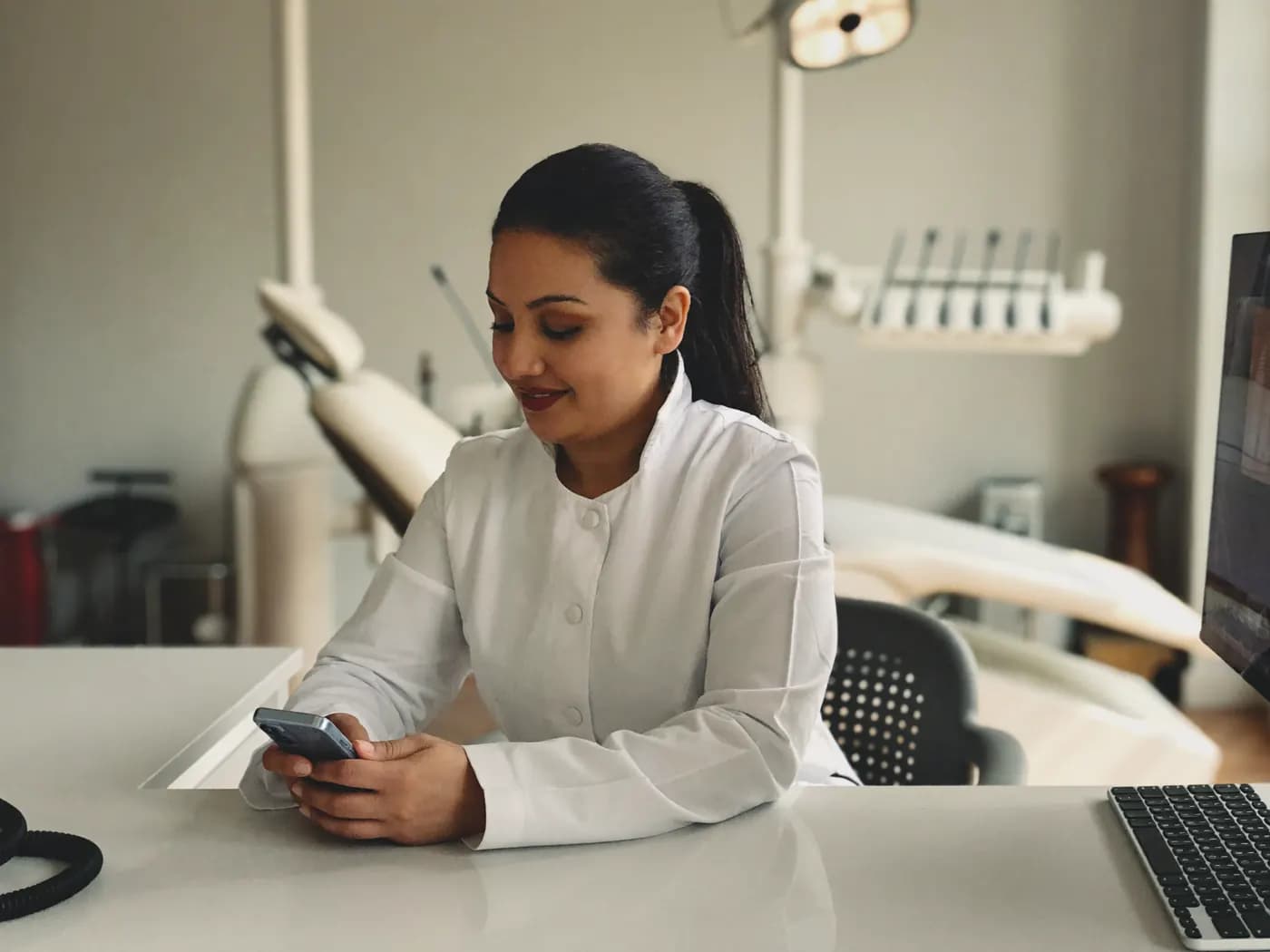 Dentista respondendo um paciente pelo celular na recepção do consultório